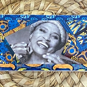 Peut inclure: Une photo en noir et blanc d'une femme souriante avec un fond à motifs bleus et dorés.