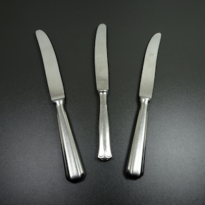 May include: Three silver table knives with rounded handles.