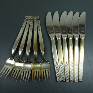 May include: Set of eight silver-tone flatware pieces, including five forks and three butter knives. The forks have a decorative pattern on the handle and the knives have a diamond pattern on the handle.