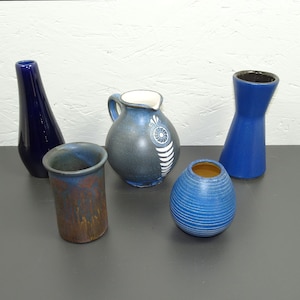 May include: Five blue and white ceramic vases of different shapes and sizes. The vases are arranged on a gray surface.