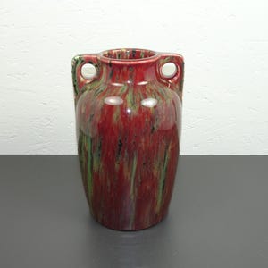 May include: A red and green glazed ceramic vase with two handles. The vase has a mottled, marbled effect.