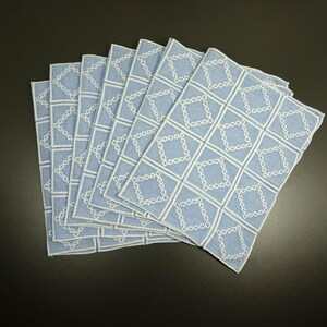 Puede incluir: Un juego de ocho manteles individuales de lino azul con patrones de diamantes bordados en blanco.
