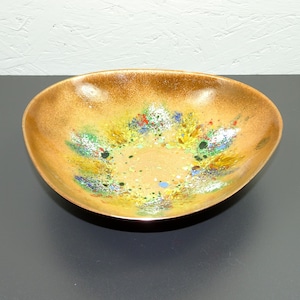 May include: A copper bowl with a speckled, multi-colored glaze. The glaze features shades of green, blue, yellow, and red.