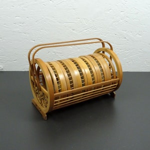 May include: A wooden rack for storing plates, made of woven bamboo. The rack has a handle and is designed to hold six plates.