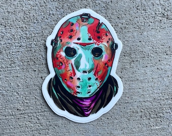 May include: A sticker of a hockey mask with red and green paint splatters. The mask has a white skull and black eye holes.