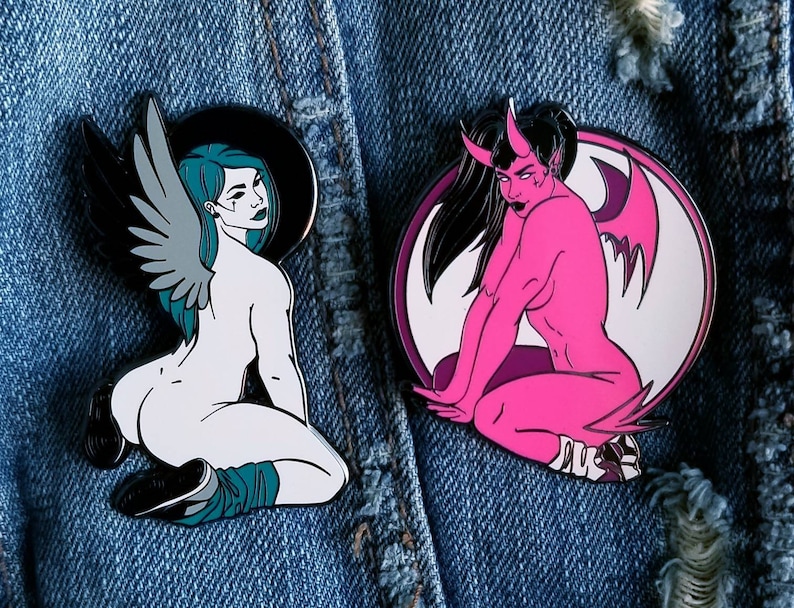 Puede incluir: Dos pines de esmalte que representan a un &aacute;ngel femenino y un demonio femenino. El pin de &aacute;ngel es blanco con alas de color turquesa y un halo. El pin de demonio es rosa con alas negras y cuernos. Ambos pines est&aacute;n sobre un fondo de mezclilla azul.