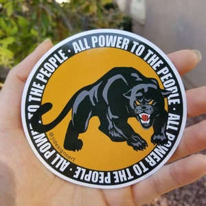 Puede incluir: Una pegatina de pantera negra con fondo amarillo. La pegatina tiene el texto "All Power to the People" escrito alrededor del c&iacute;rculo.