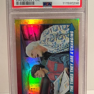 May include: A graded trading card featuring characters from Back to the Future II. The card has a rainbow foil design and includes the text "2013 Topps 75th Anniv." and "Back to the Future II Rainbow Foil". The card is graded as Mint 9.