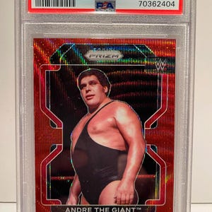 Könnte beinhalten: Eine 2022 Prizm WWE Trading Card mit Andre the Giant in einem schwarzen Wrestling-Singlet. Die Karte hat ein Ruby Wave Prism Design mit dem Text "ANDRE THE GIANT" unten. Die Karte ist mit Mint 9 bewertet.
