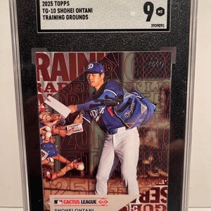 May include: A 2025 Topps Shohei Ohtani Training Grounds baseball card graded SGC 9 MT. The card features Ohtani in a blue Dodgers jersey and white pants, signing autographs for fans. The card is encased in a black SGC protective slab with a label.