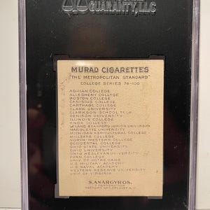 Puede incluir: Una tarjeta de intercambio vintage de cigarrillos Murad con una lista de universidades de la serie universitaria est&aacute;ndar metropolitana 76-100. La tarjeta es de color crema con texto negro.