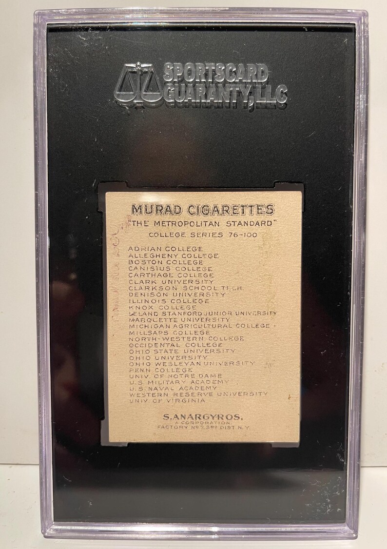 Puede incluir: Una tarjeta de intercambio vintage de cigarrillos Murad con una lista de universidades de la serie universitaria est&aacute;ndar metropolitana 76-100. La tarjeta es de color crema con texto negro.