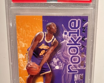 May include: A 1996 Skybox Premium Kobe Bryant rookie card, graded and encased. The card features a photo of Bryant in a Lakers uniform, holding a basketball. The card is graded as Mint 9.