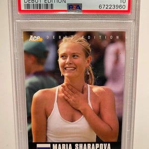May include: A graded trading card featuring Maria Sharapova from 2005. The card is labeled "Ace Authentic Debut Edition" and includes the text "Maria Sharapova" and the Russian flag. The card is encased in a protective holder.