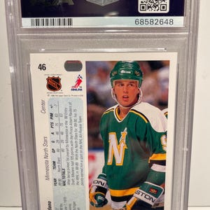 May include: A hockey card featuring Mike Modano, a center for the Minnesota North Stars. The card is from the 1989-90 Upper Deck series and features a photo of Modano in his North Stars uniform. The card also includes Modano's statistics for the 1989-90 season.