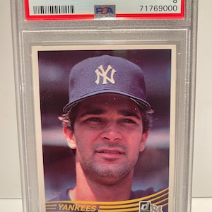 May include: A 1984 Donruss baseball card featuring Don Mattingly of the Yankees. The card is graded NM-MT 8 and encased in a protective holder. The card has the text "1984 Donruss Don Mattingly" and "Yankees" printed on it.