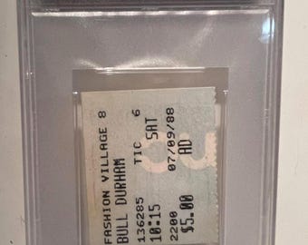 May include: A PSA-graded 1988 Bull Durham cinema ticket stub from AMC Fashion Village 8 in Orlando, FL, dated 9 July. The ticket is encased in a clear plastic holder with a white label at the top displaying the film title, location, and date.