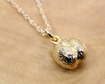 May include: A gold necklace with a detailed, textured pendant shaped like a walnut.