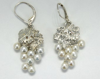 May include: Silver earrings featuring a grapevine design with white pearls dangling from the leaves.