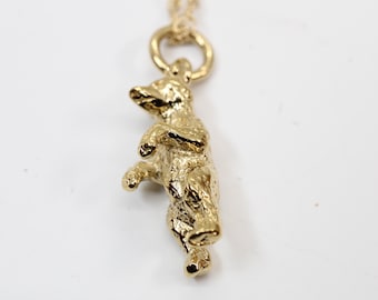 May include: A gold-toned bear pendant necklace. The bear is standing on its hind legs with its front paws raised. The necklace has a delicate chain.