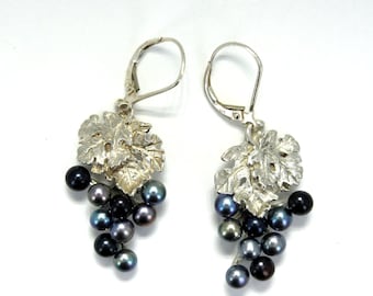 May include: Silver dangle earrings with a grapevine design and black pearls.