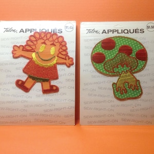 May include: Two vintage Talon appliqués on their original packaging. One features a smiling cartoon character with orange hair and a red dress. The other is a green mushroom with red spots. Both are on cards with the text "SEW-RIGHT-ON".