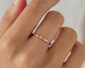 May include: A delicate gold ring with a small, light green gemstone set in the center.