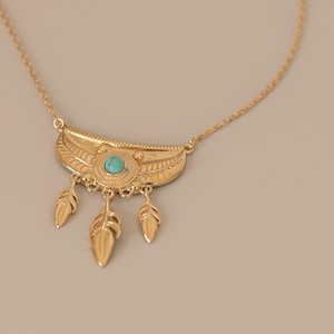 Può includere: Una collana d'oro con una pietra turchese e tre ciondoli a forma di piuma.