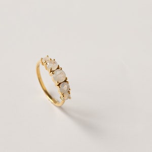 May include: A gold ring with five white moonstone gemstones set in a row.