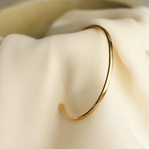 Dainty open bangle oval shape and very thin made of sterling silver and 24k gold plated silver
