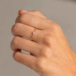 Fine six-claw solitaire ring with a small amethyst-colored zirconia in the center made of 925 sterling silver and plated in 24k gold