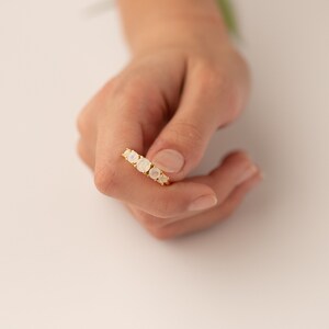 May include: A gold ring with five white moonstone gemstones set in a row.