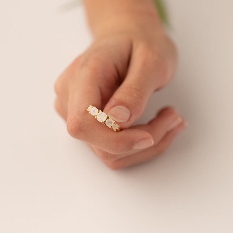 May include: A gold ring with five white moonstone gemstones set in a row.