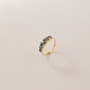 May include: A gold ring with five blue gemstones set in a row.