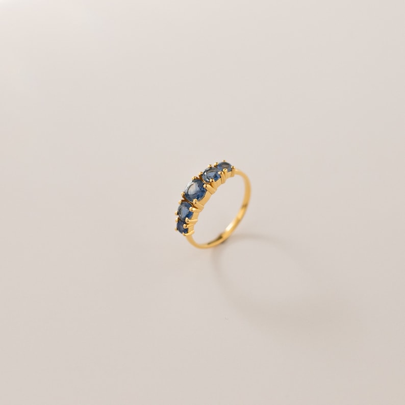May include: A gold ring with five blue gemstones set in a row.