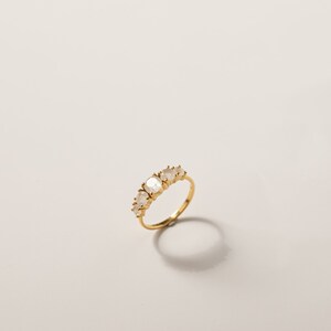 May include: A gold ring with five oval-shaped moonstone gemstones set in a band.