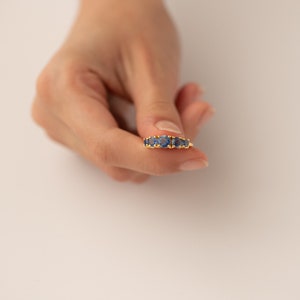 May include: A gold ring with a row of blue gemstones.