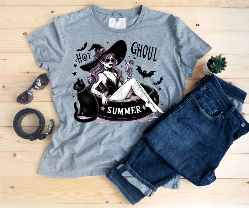 May include: Gray t-shirt with a graphic of a witch in a pool float with a black cat. The text "Hot Ghoul Summer" is printed on the shirt.