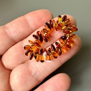 May include: A strand of amber beads in a warm honey color. The beads are oval shaped and strung on a thin wire.