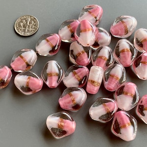 May include: A collection of pink and white glass beads with gold accents. The beads are irregularly shaped and have a translucent appearance.