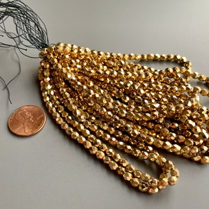 May include: A strand of gold-colored faceted glass beads with a black tassel. The beads are approximately the size of a US penny.