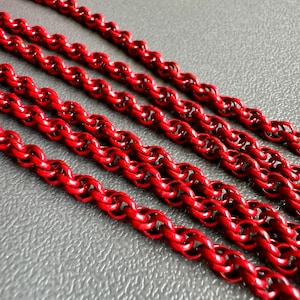 May include: Four strands of red chain link, each with a twisted rope design, lie on a gray textured surface.