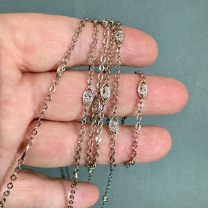 May include: A silver chain necklace with oval-shaped links that are set with small clear stones.
