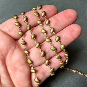 Puede incluir: Primer plano de una cadena dorada con eslabones ovalados. La cadena está hecha de metal y tiene un acabado liso y pulido.