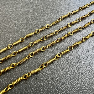 May include: Four strands of gold-colored chain with a coiled link design.