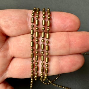 May include: Four strands of gold-toned chain with round and cylindrical beads.