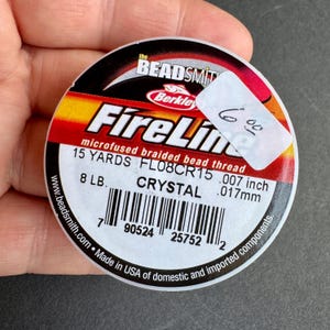 May include: A spool of FireLine microfused braided bead thread in crystal color. The spool is labeled with 15 yards, 8 lb, 0.007 inch, and 0.017 mm. The label also includes a barcode and the text "Made in USA of domestic and imported components."