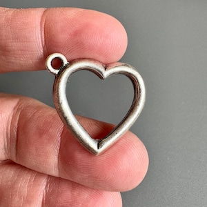 May include: Silver open heart charm pendant with a loop at the top for attaching to a necklace or bracelet.