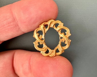 Könnte beinhalten: Ein goldfarbener Metallring mit einem dekorativen, verzierten Design. Der Ring besteht aus komplizierten, wirbelnden Mustern, die an Blätter oder Ranken erinnern.