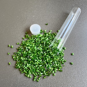 銀色の縁取りが施された緑色のビューグルビーズ。10グラム入りチューブで販売。SKU 11226